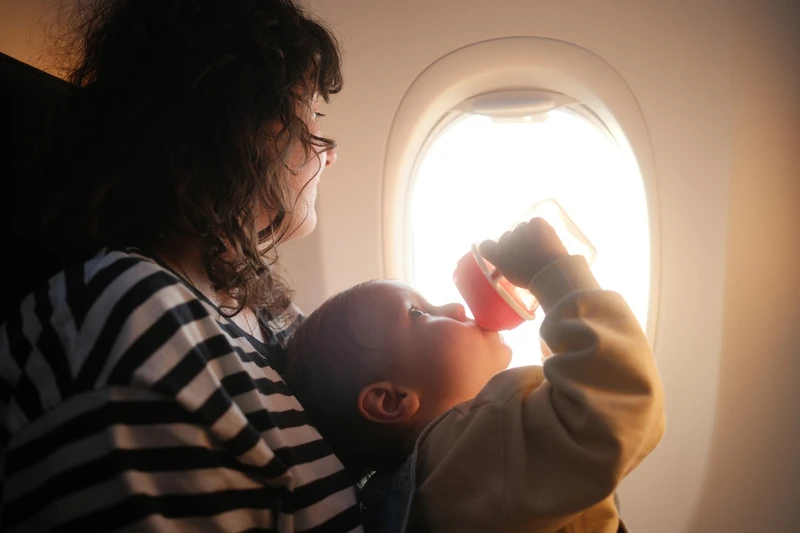 Un niño está bebiendo agua en un avión con su madre. Un niño está bebiendo agua en un avión con su madre.
