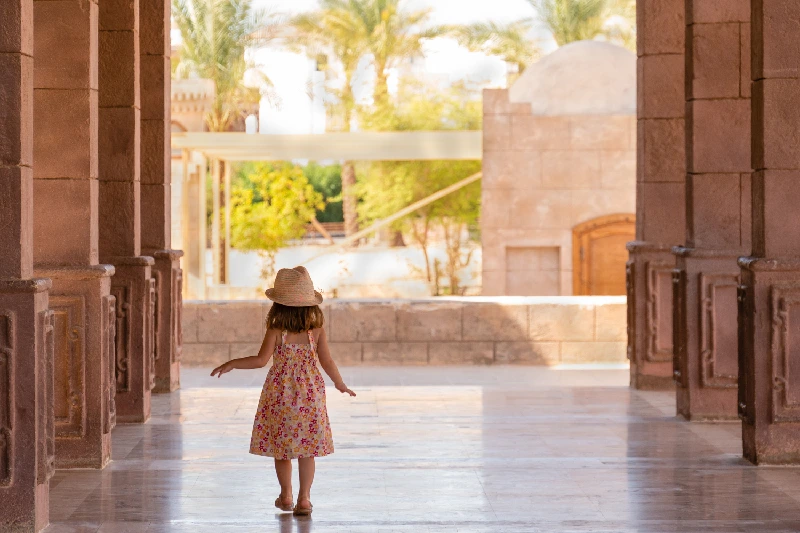 Una linda niña camina lentamente por el pórtico entre las columnas. Mezquita El Mustafa, Sharm El Sheikh, Egipto.
