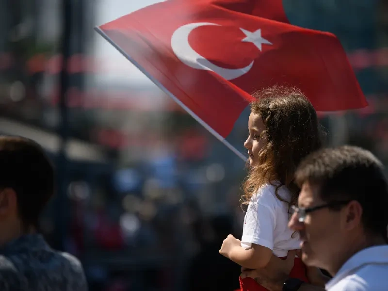 A young girl proudly holds a Turkish flag on Victory Day.