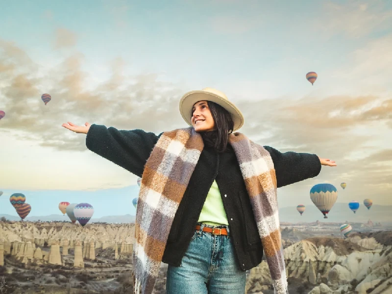 Woman watching hot air balloons over Cappadocia’s Love Valley.
