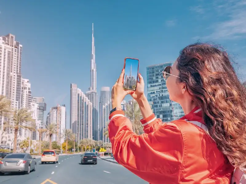 Happy traveler taking photos with Burj Khalifa in Dubai.