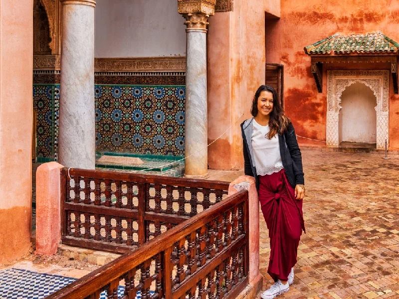 A woman in traditional Moroccan attire walking through Marrakech streets.