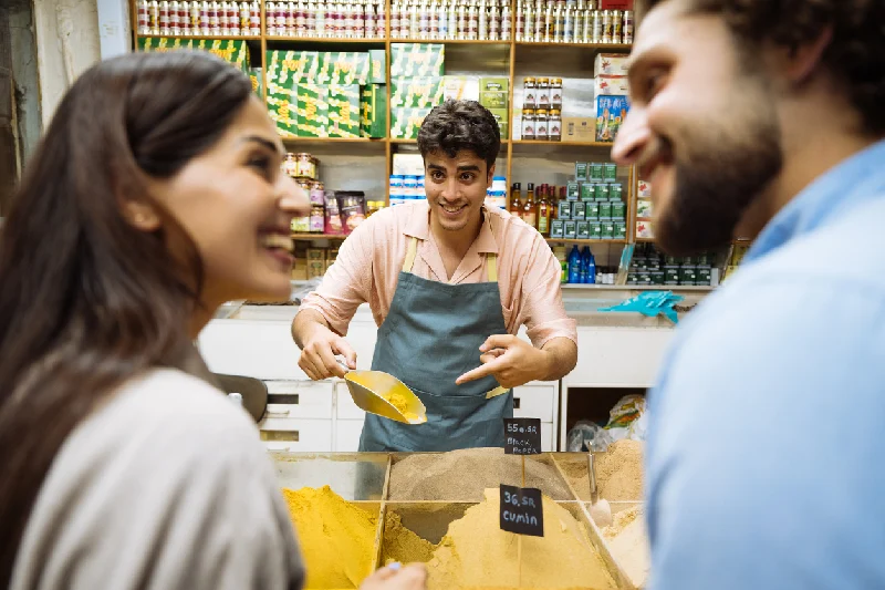 Vendedor mostrando especias a una pareja en un mercado
