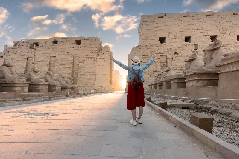 viaggiatrice a braccia aperte all’ingresso del tempio di karnak a luxor, viaggio in egitto cosa sapere
