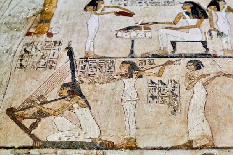 Músicas y danzarinas del Antiguo Egipto durante una celebración religiosa, representadas en un fresco con instrumentos tradicionales.