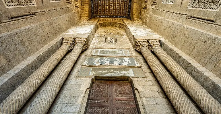 La mezquita Al-Rifai en el antiguo Cairo, Egipto. Una antigua sala de piedra con intrincadas tallas y una gran puerta de madera.