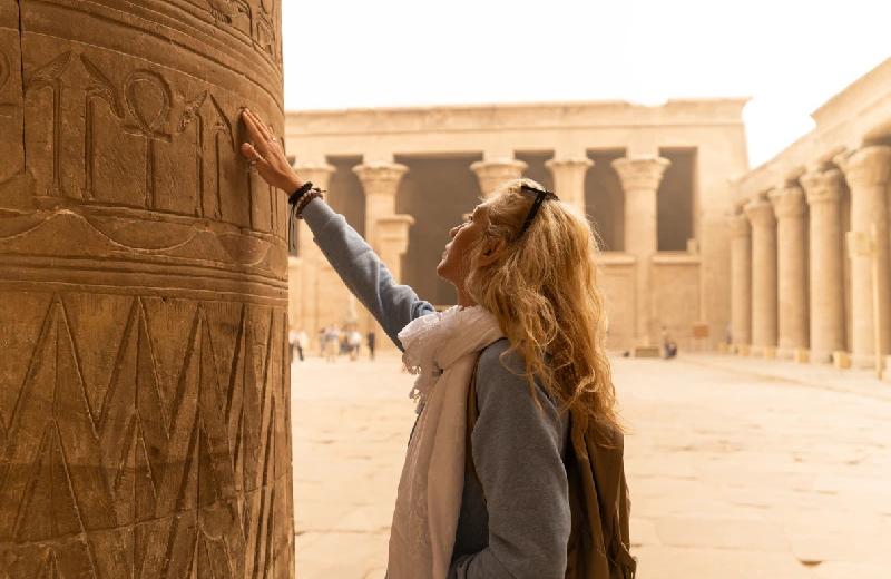 turista donna che tocca le colonne del tempio di horus a edfu, crociera nilo e cairo