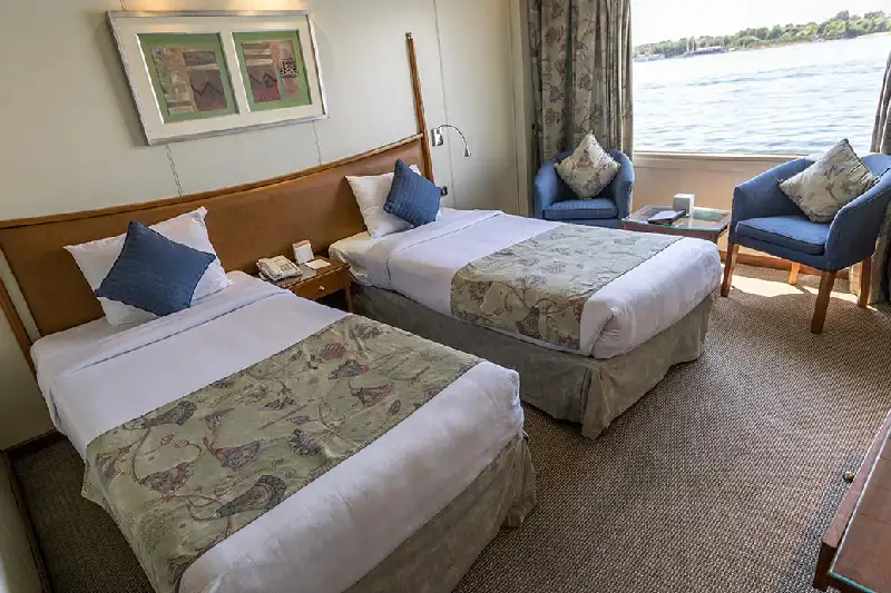 due letti e una finestra in una cabina a bordo di movenpick royal lily