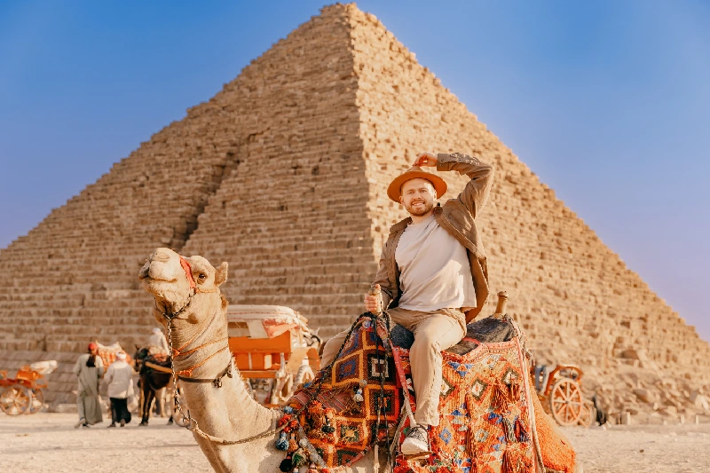 Un uomo a dorso di un cammello davanti alle piramidi, viaggio capodanno egitto