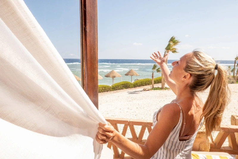 donna che apre le tende nella stanza, tour egitto piramidi e mare