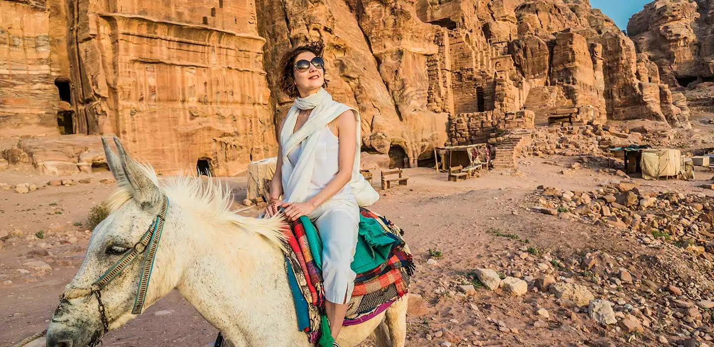 a woman wearing white dress riding a donkey in petra 