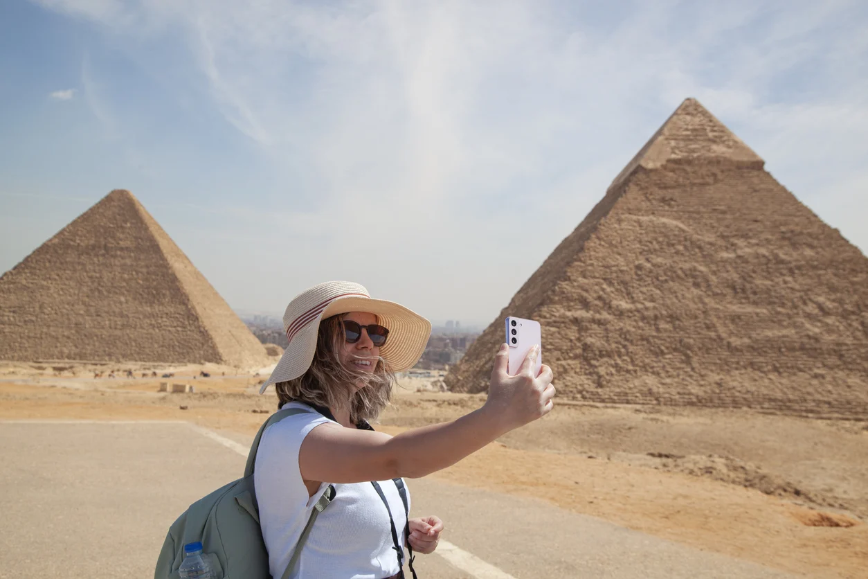 tourist woman takes selfie with pyramids of giza, Gems of Egypt and Nile Tour