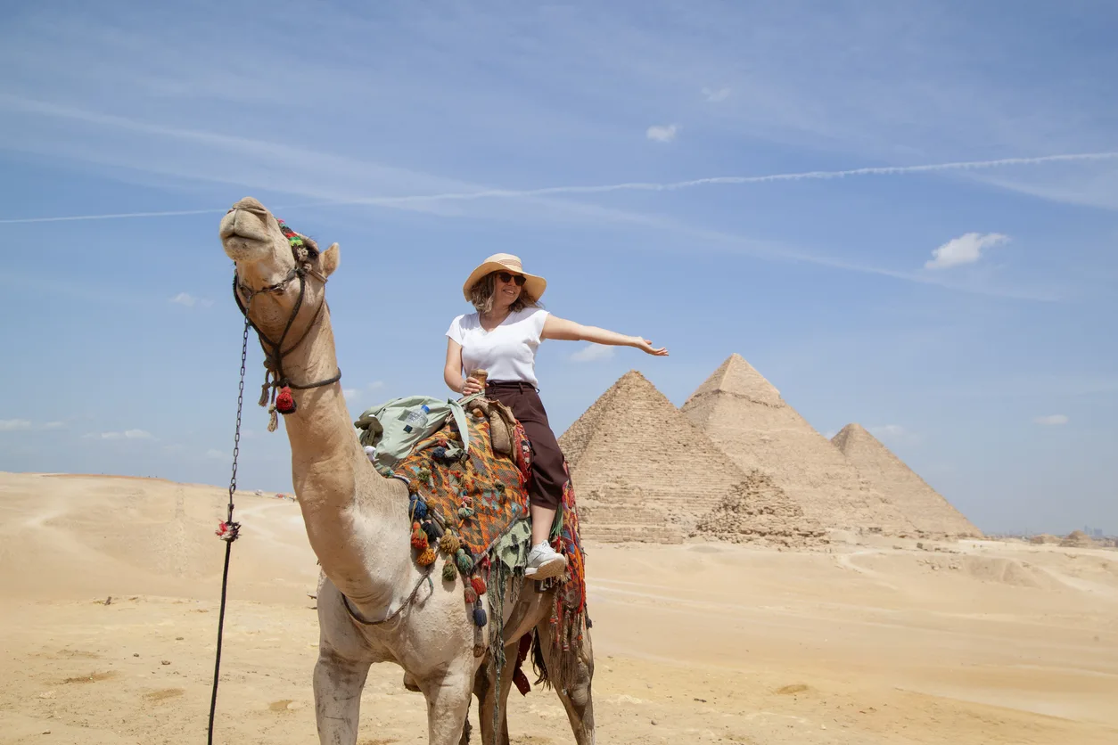 female tourist riding a camel in front of pyramid of giza, Alexandria Shore Excursions