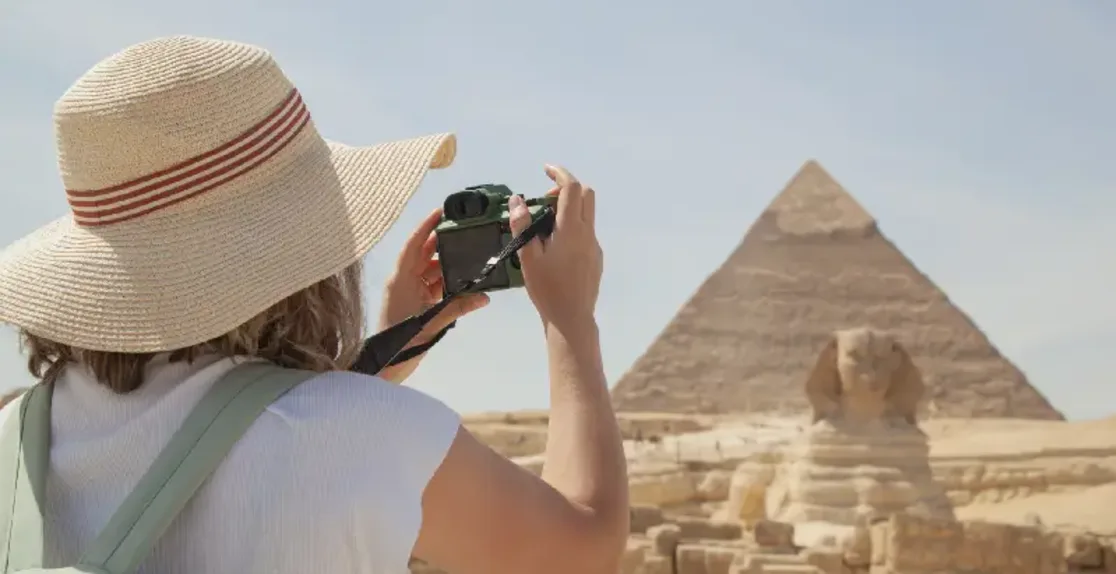una donna scatta una foto per la piramide , dove andare in egitto a dicembre