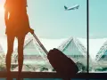 Viajero con maleta observando un avión despegar desde el aeropuerto en Egipto.