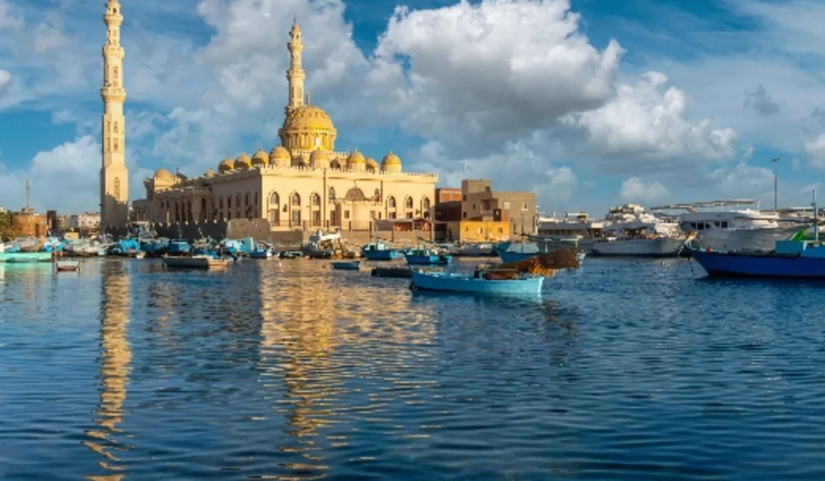 La mezquita Al Mina se refleja en el agua con barcos de pesca al atardecer en Hurghada, Egipto.