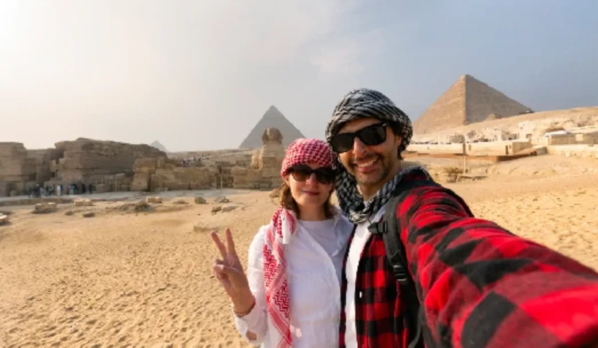 Pareja joven se toma una selfie frente a las Grandes Pirámides de Giza.