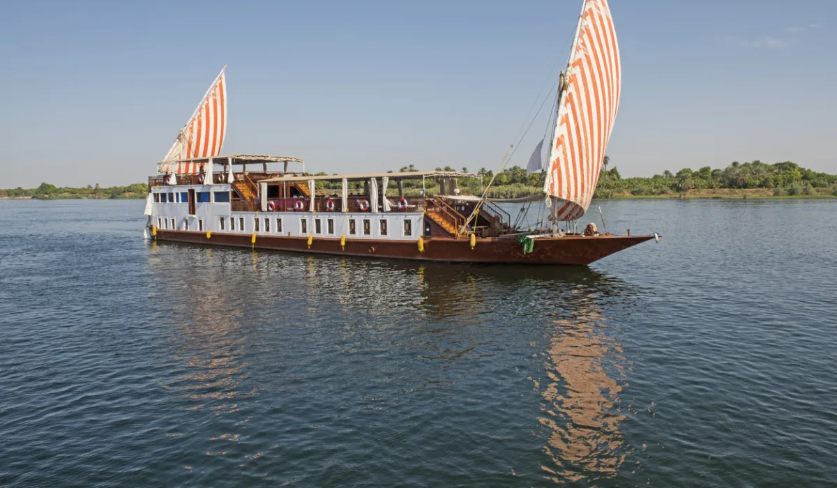 Large luxury traditional Egyptian dahabeya river boat sailing on the Nile with reflection