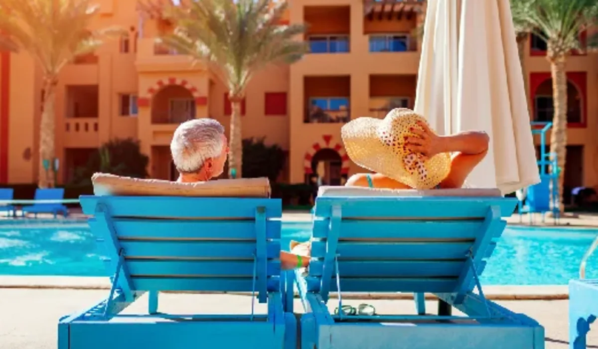 pareja-senior-relajandose-junto-a-la-piscina-en-tumbonas-disfrutando-de-las-vacaciones-de-verano