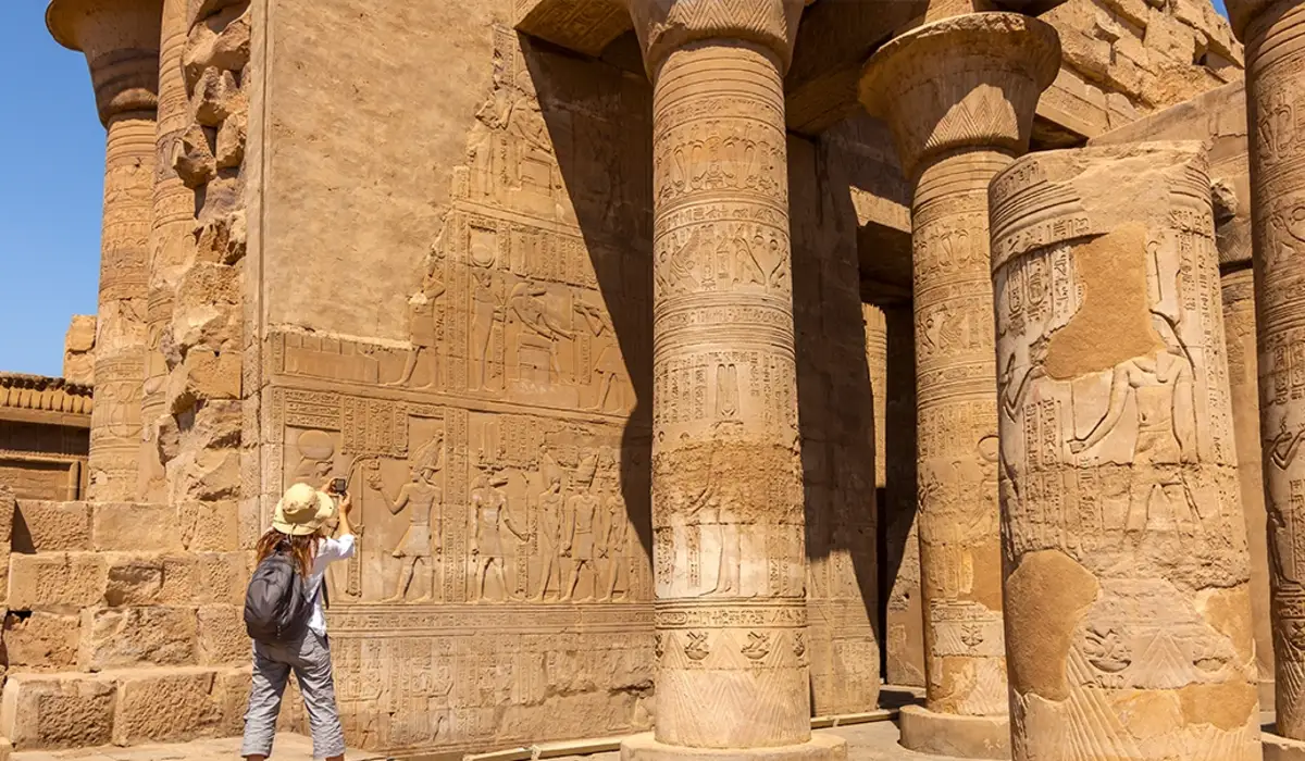 a female tourist wearing a hat captures a photo in kom ombo temple, Kom Ombo Temples