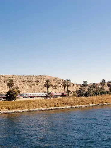 Tren y paisaje a lo largo del río Nilo entre Luxor y Asuán, Egipto.