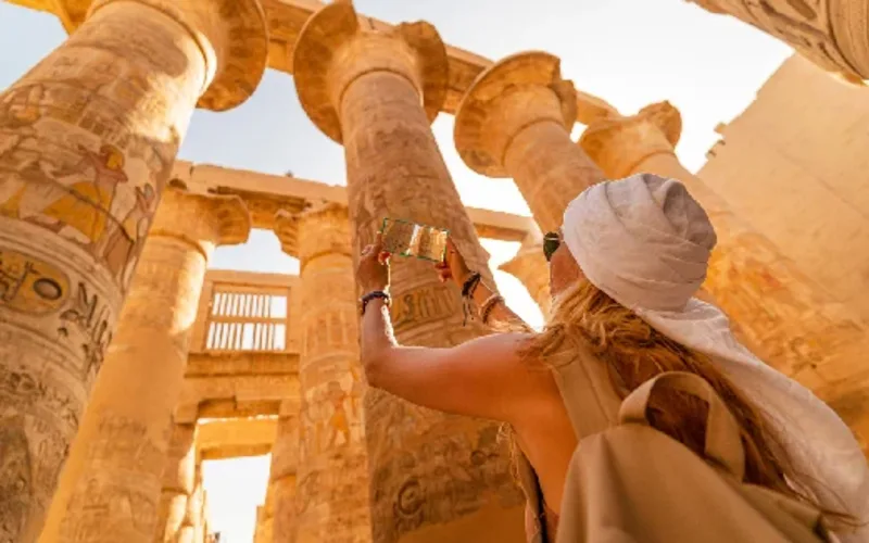 Turista femenina camina entre las columnas de la Gran Sala Hipóstila del Templo de Karnak.