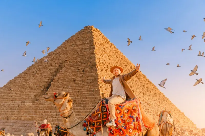 Uomo in groppa ad un cammello davanti alle Piramidi durante il viaggio in Egitto