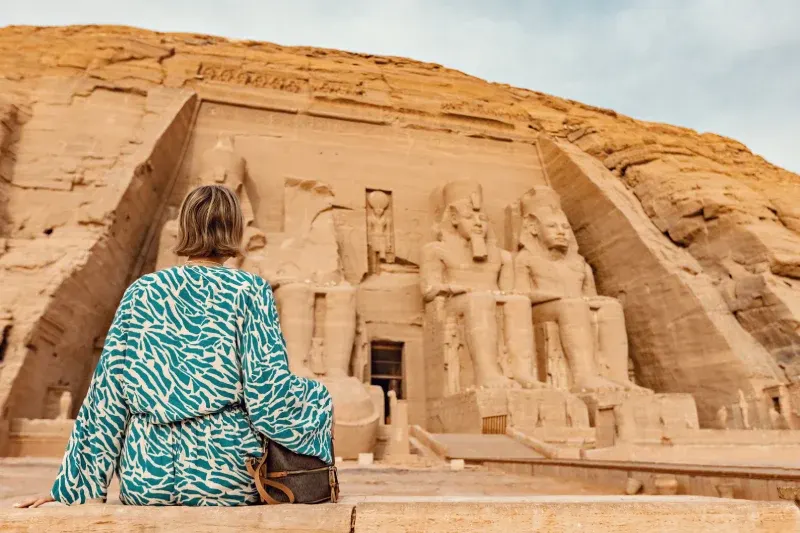 Donna seduta davvanti ad Abu Simbel per ammirare una delle meraviglie del tour Egitto classico tra Cairo e crociera sul nilo.