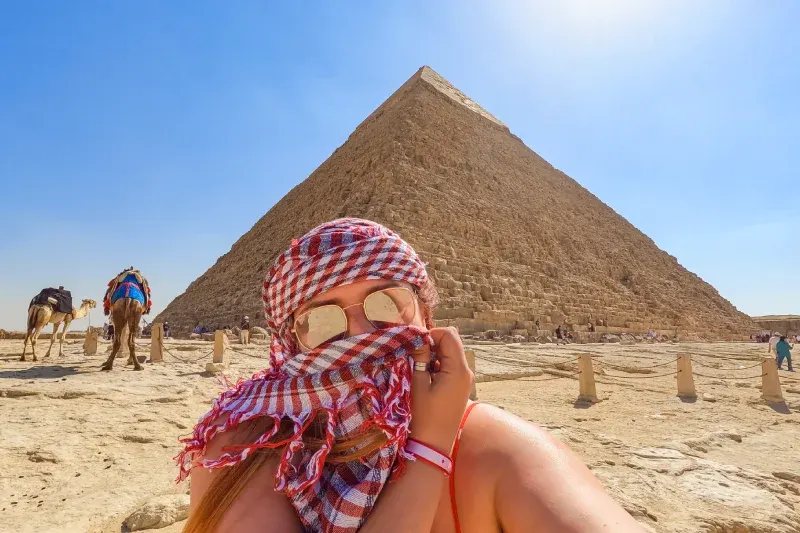 Ragazza che si scatta un selfie in Khefia e occhiali davanti alla Piramide di Chefren
