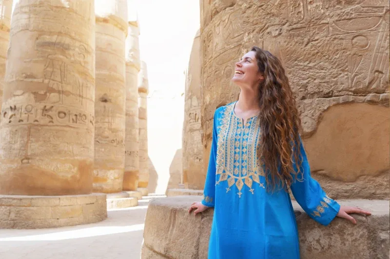 Donna in abito tradizionale tra i colonnati di un tempio egizio