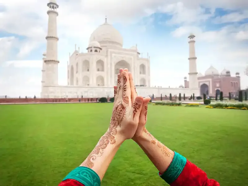 Mani congiunte in segno di spiritualità davanti al Taj Mahal, tra le cose da vedere almeno una volta in India.