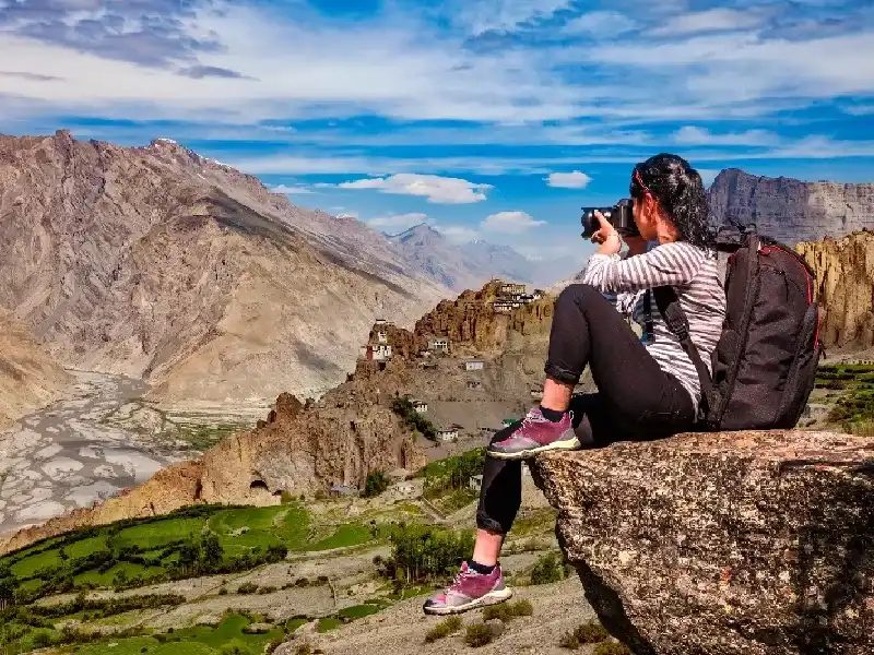 Donna che scatta una foto panoramica con una macchina fotografica grazie all'ottimo meteo in India