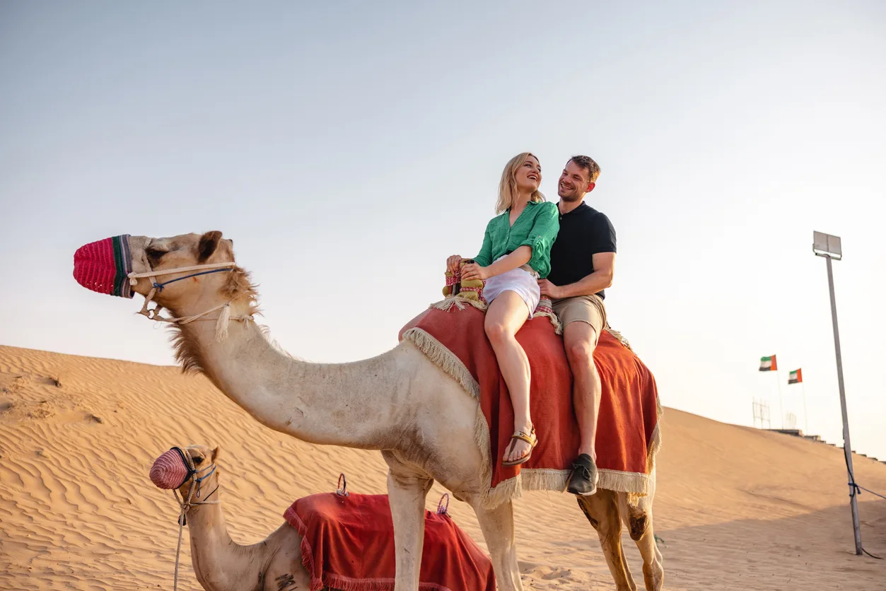 Una coppia cavalca un cammello nel deserto a Dubai. Città di Dubai