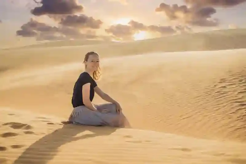 una donna che si rilassa in cima a una duna di sabbia nel deserto del Sahara in Marocco, Deserto del sahara marocco