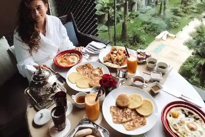 Donna al tavolo per la colazione a buffet con frutta, cosa mangiare in Marocco