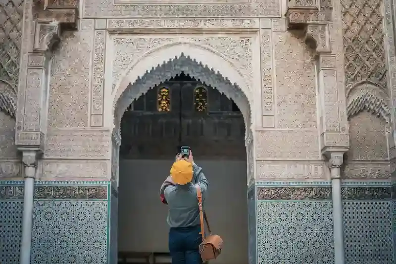 Turista femminile cinese asiatica che fotografa e ammira la moschea di Fez, città imperiali marocco