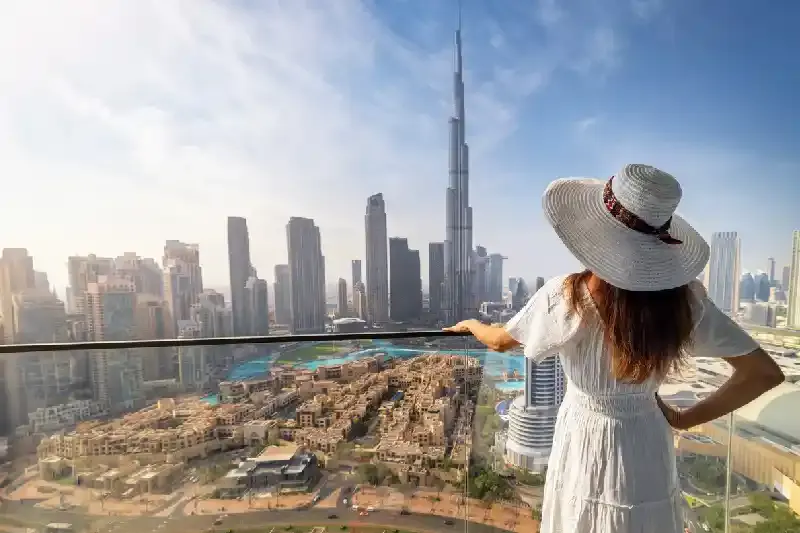 Una donna elegante in abito bianco ammira la vista dello skyline del centro di Dubai, il burj khalifa | il grattacielo burj khalifa
