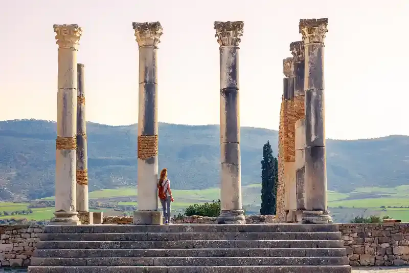 Turista donna che si gode la bellissima colonna e rovina, volubilis cosa vedere