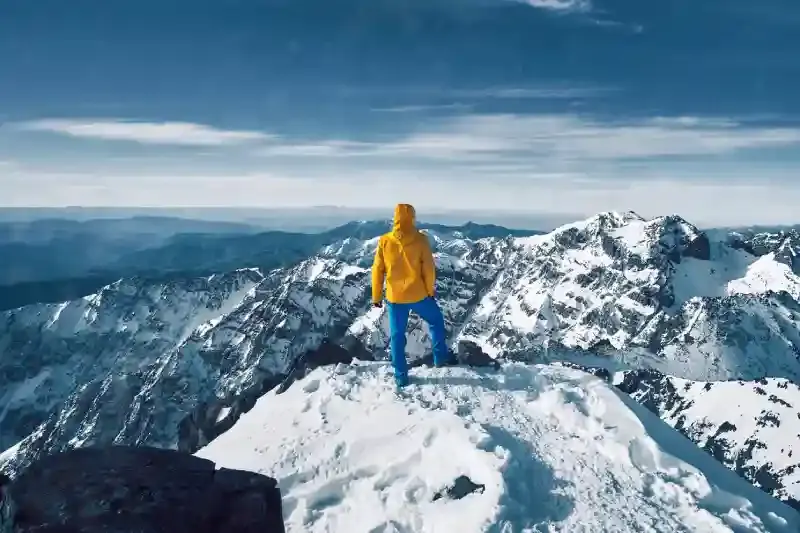 Turista da solo in piedi e in meditazione sulla montagna dell'Atlante coperta di neve, montagne marocco