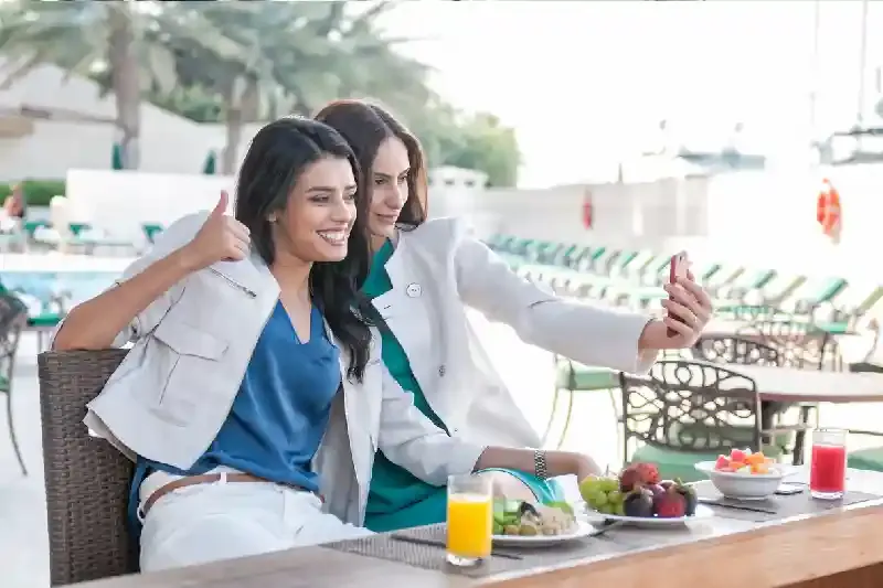 Donne mediorientali che si scattano selfie, bar a bordo piscina, dove mangiare dubai
