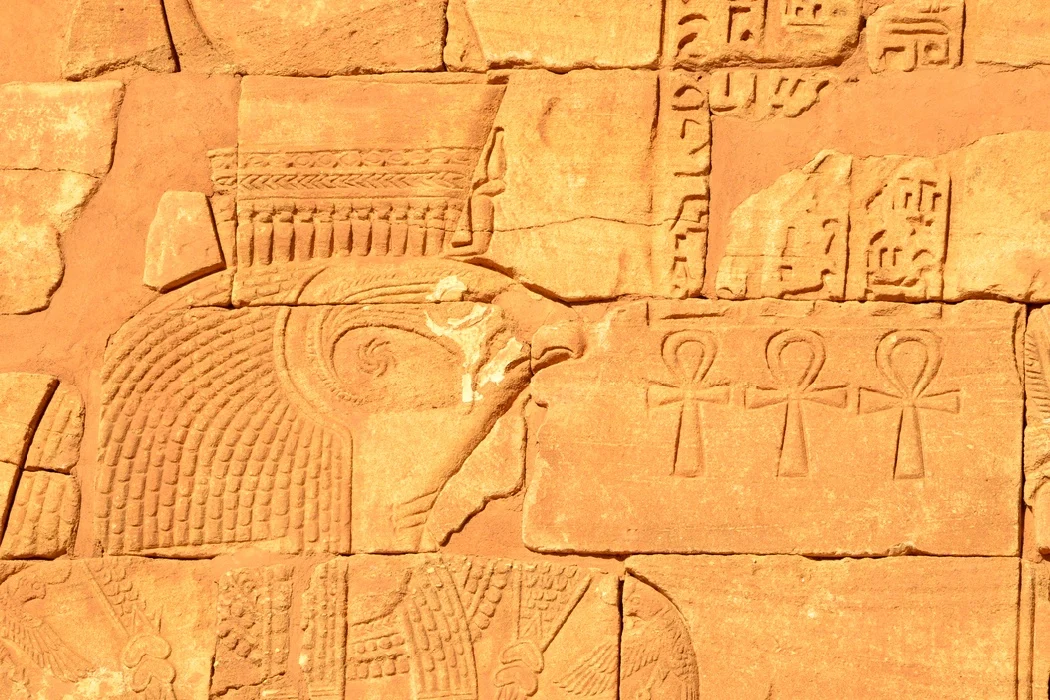 Relieve egipcio antiguo con representaciones de símbolos anj y la cabeza de un dios halcón
