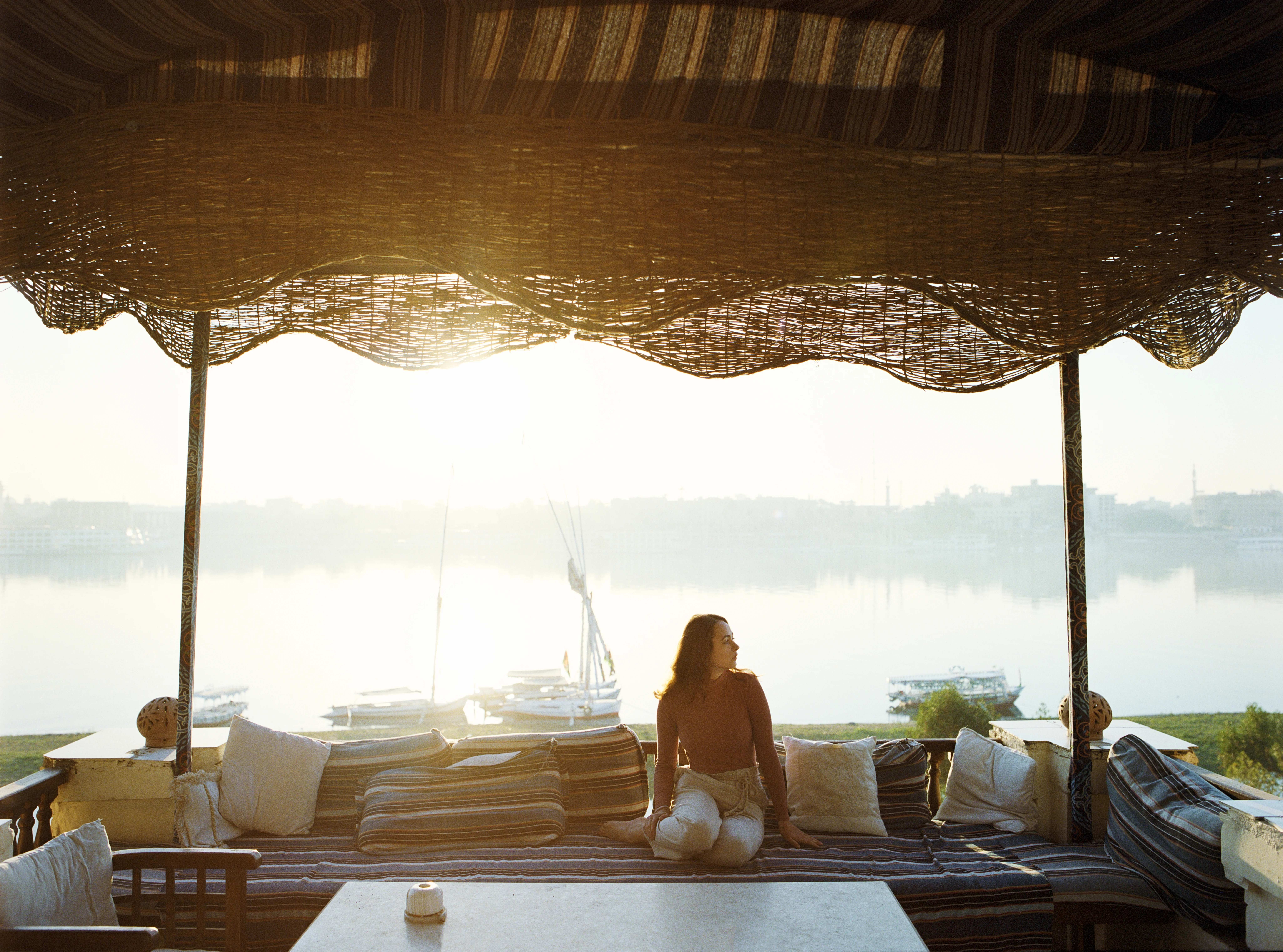 Mujer joven sentada en la terraza mirando el Nilo al atardecer en Luxor