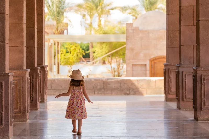 Una linda niña camina lentamente por el pórtico entre las columnas. Mezquita El Mustafa, Sharm El Sheikh, Egipto.