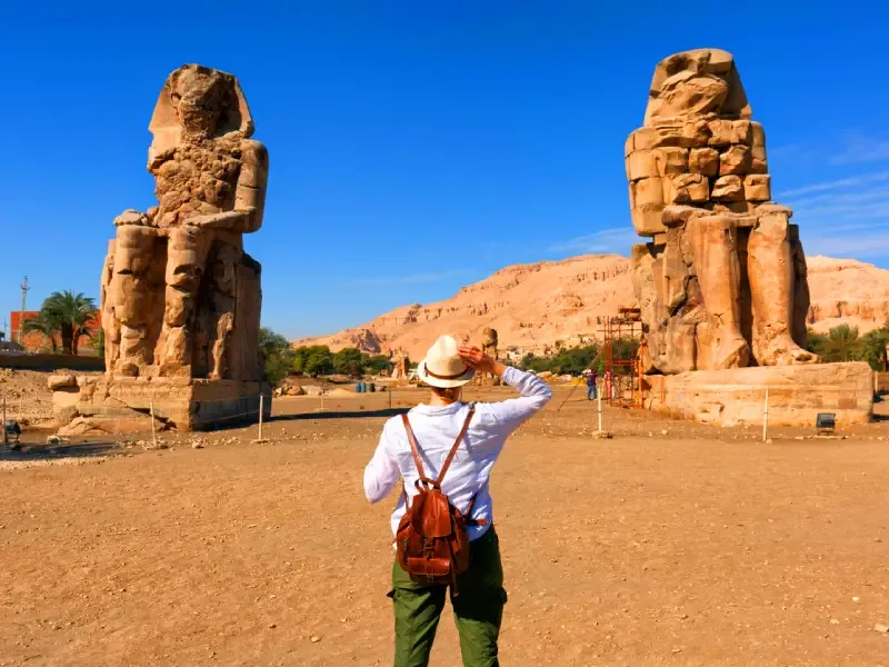 Viaggiatrice di spalle davanti ai Colossi di Memnone