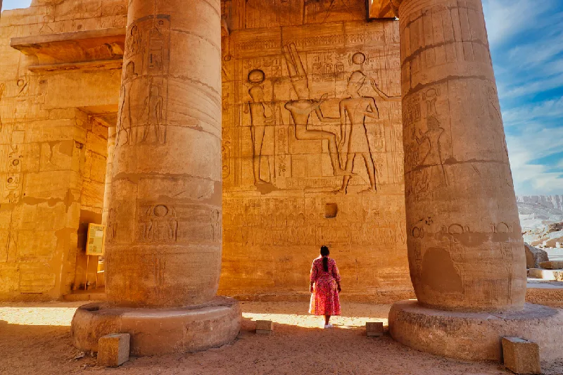 Un visitante admira el relieve mural de Ramsés II recibiendo bendiciones de Amón y Ptah al final de la galería hipóstila principal del templo mortuorio de Ramsés.