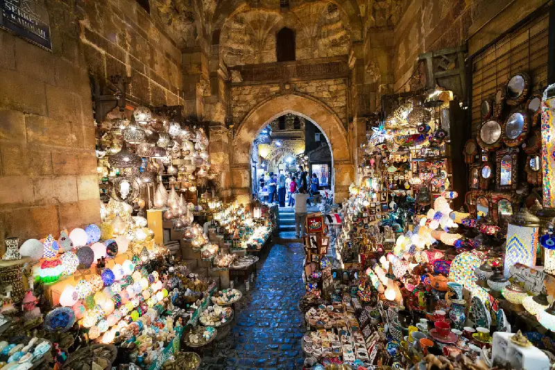 Calles iluminadas por faroles y repletas de productos tradicionales egipcios en el bazar de Khan El-Khalili por la noche.
