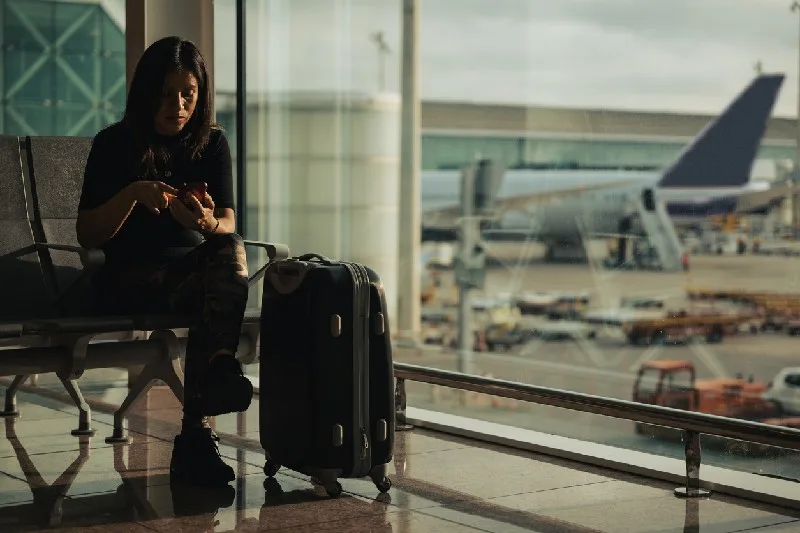 Mujer con maleta mirando un avión despegar en el aeropuerto