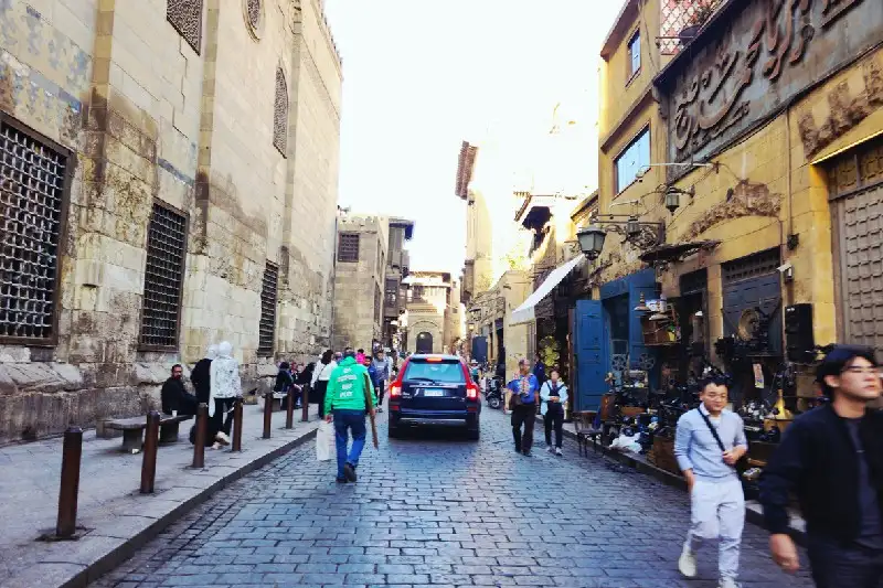 Calle concurrida en El Cairo con turistas y locales, mostrando arquitectura tradicional y actividad diaria.