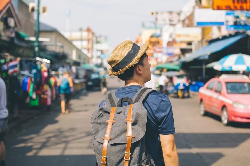 Turista caminando por las calles de Hurghada con mochila y sombrero, disfrutando de un día soleado en Egipto.
