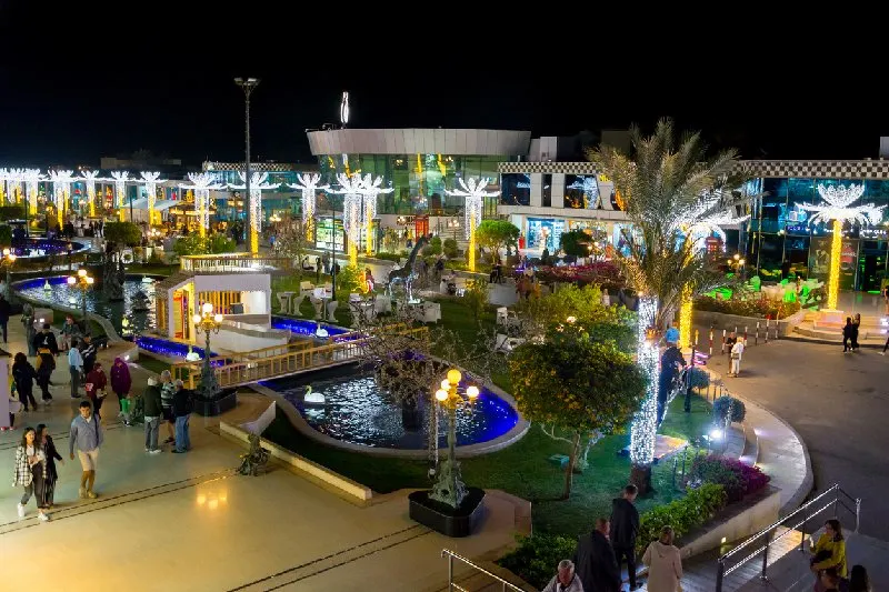 Vista nocturna de SOHO Square en Sharm El Sheij con luces y jardines iluminados.